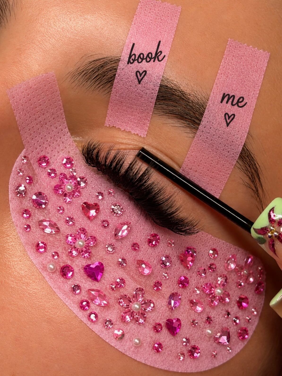 Lash pad decorated with pink gems and tape reading book me